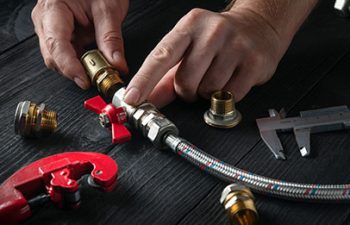 A worker in a nut on a boiler water heater with a plumbing wrench