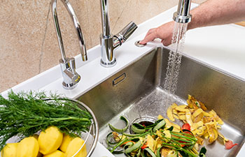 Turning on a disposer in a modern kitchen to remove food waste.